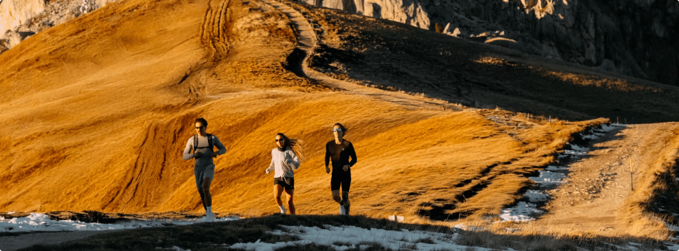 Atletas correndo em trilha de montanha ao pôr do sol