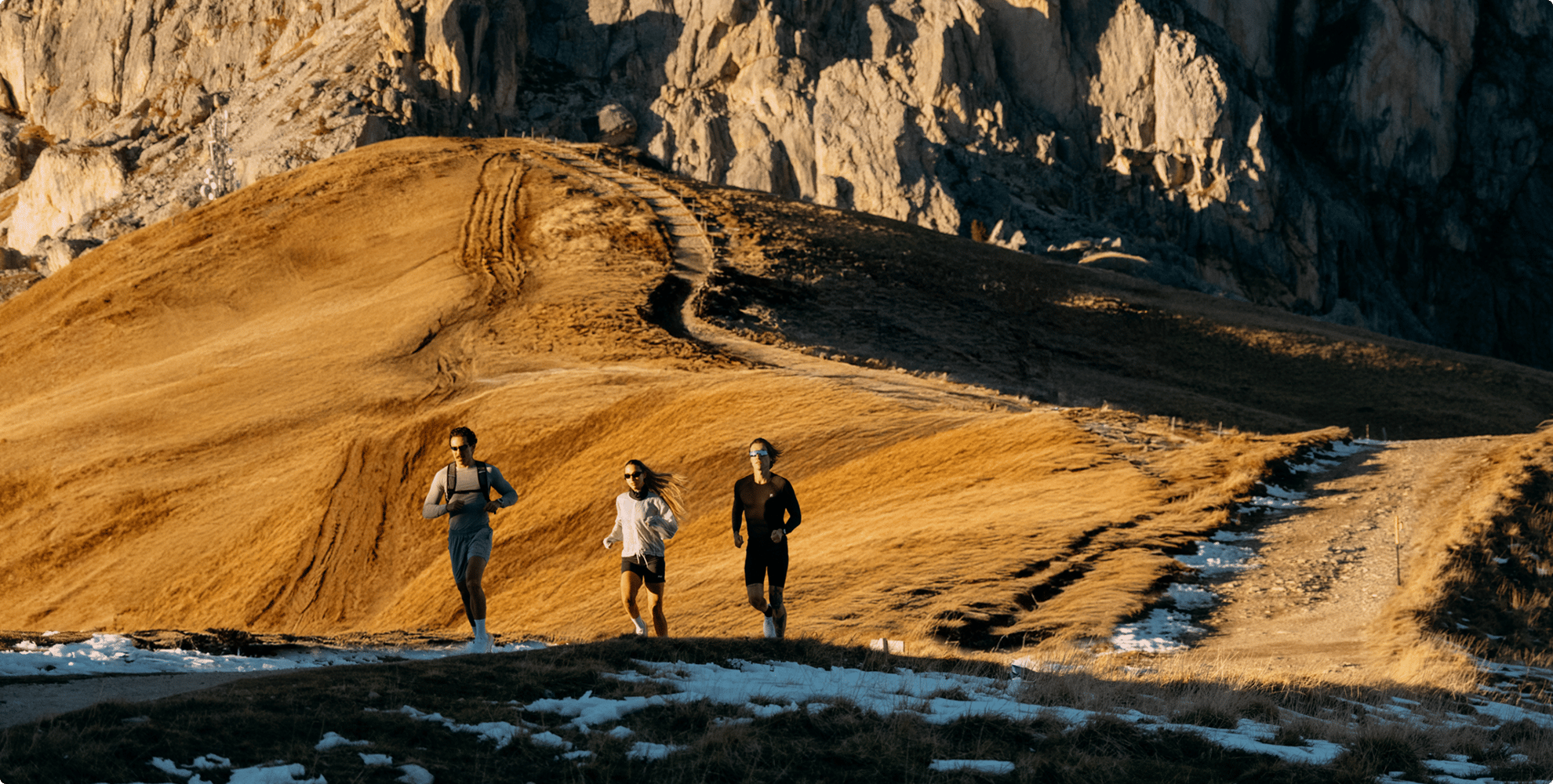 Atletas correndo em trilha de montanha ao pôr do sol