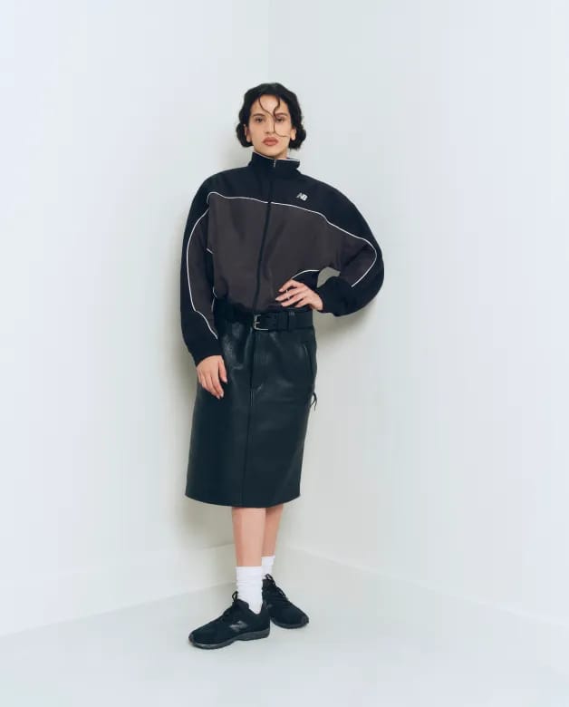 Mulher sentada em banquinho de madeira com calça de moletom cinza e 204L off-white
