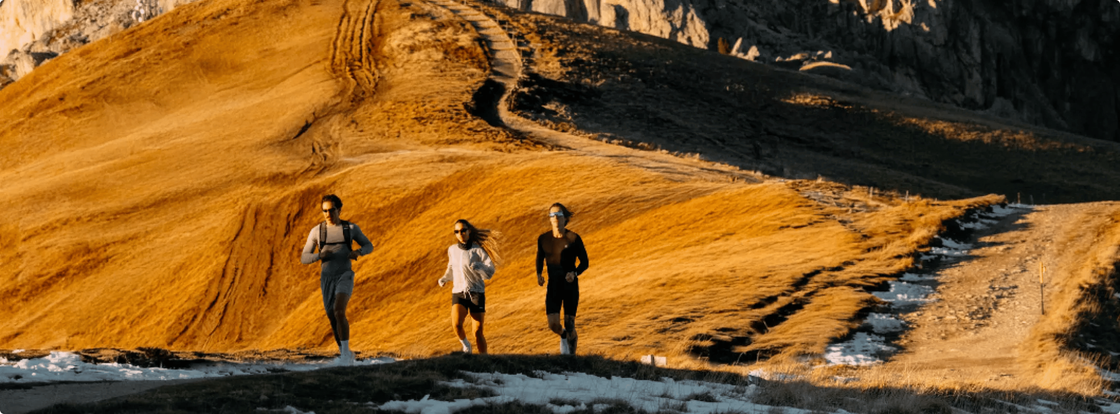 Atletas correndo em trilha de montanha ao pôr do sol