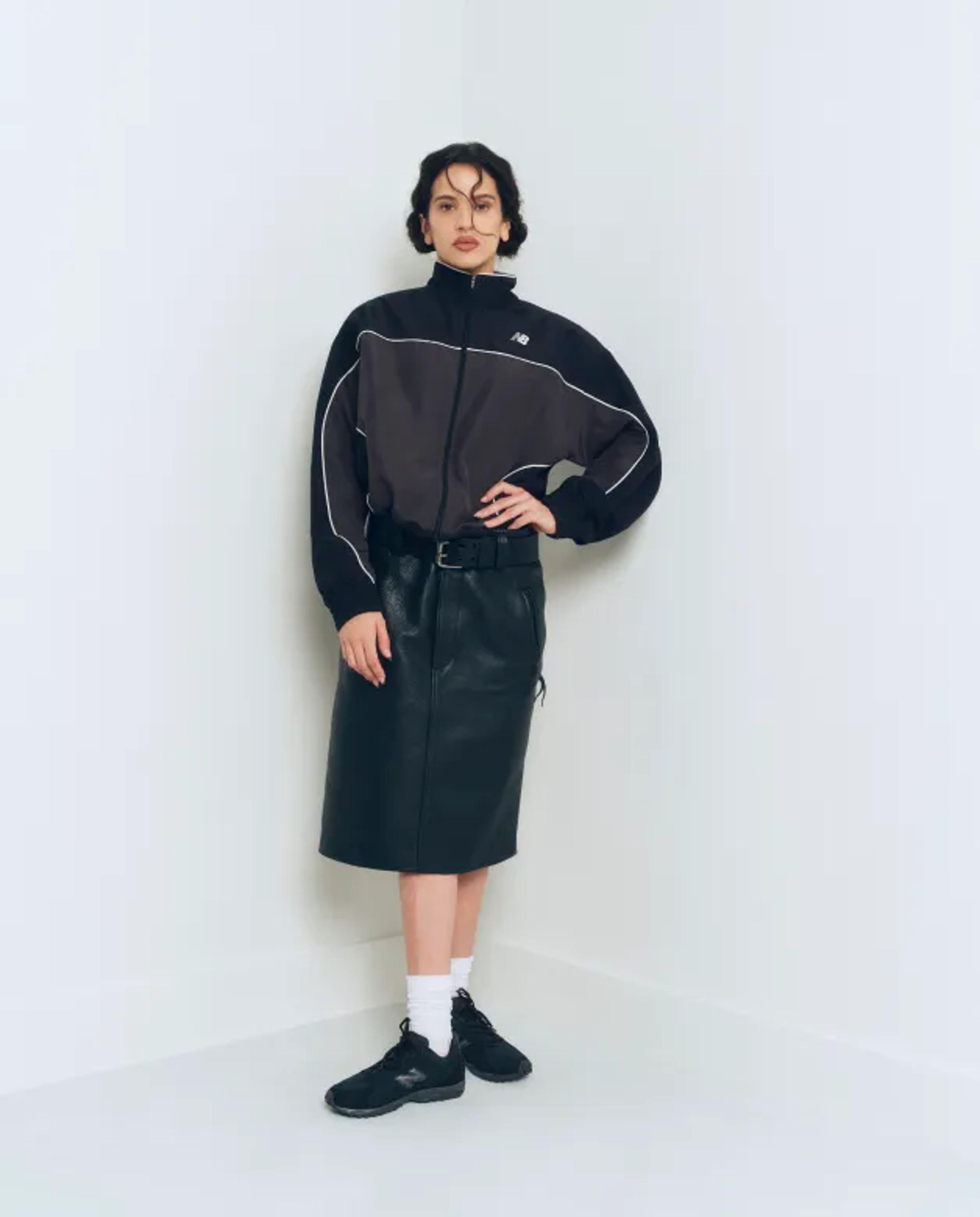 Mulher sentada em banquinho de madeira com calça de moletom cinza e 204L off-white